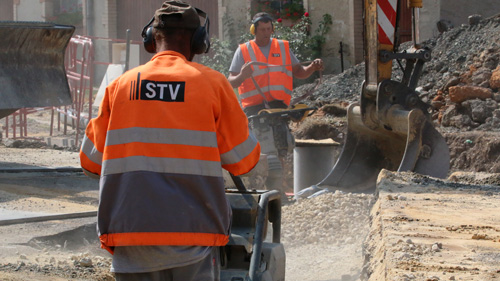 Deux ouvriers rebouchent et tasse une tranché de chantier